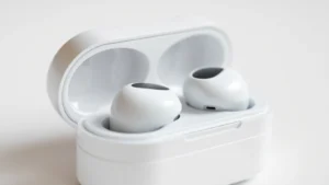 Close-up of premium wireless earbuds in charging case, white and metallic finish, soft studio lighting, shallow depth of field, minimalist composition
