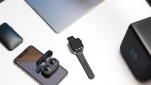 A modern desk workspace with multiple tech gadgets including a smartphone, wireless earbuds in their case, a smartwatch, and a portable speaker arranged neatly on a clean surface